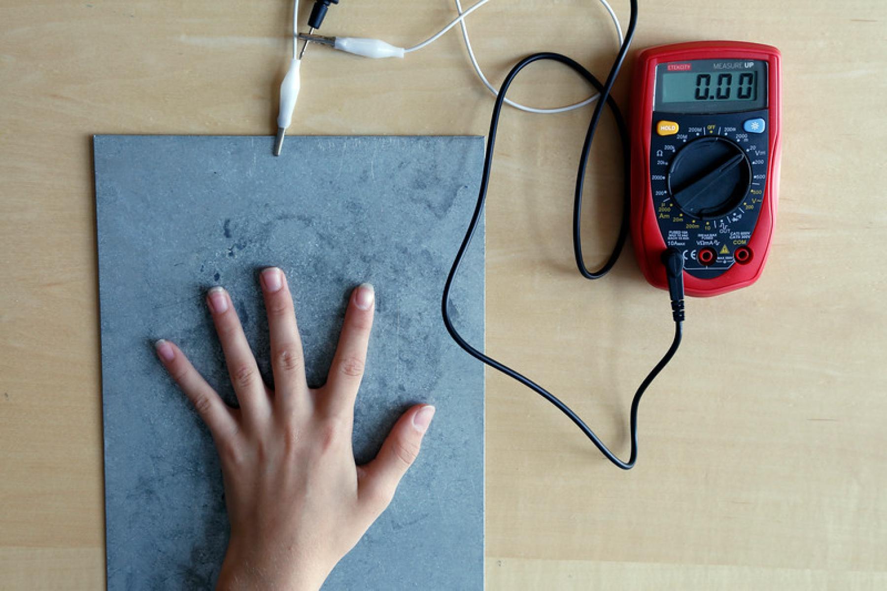 Participant's hands touching the steel plate, connected to a multimeter