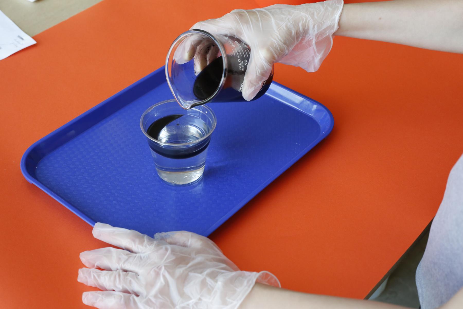 Participant pouring oil into cup of water