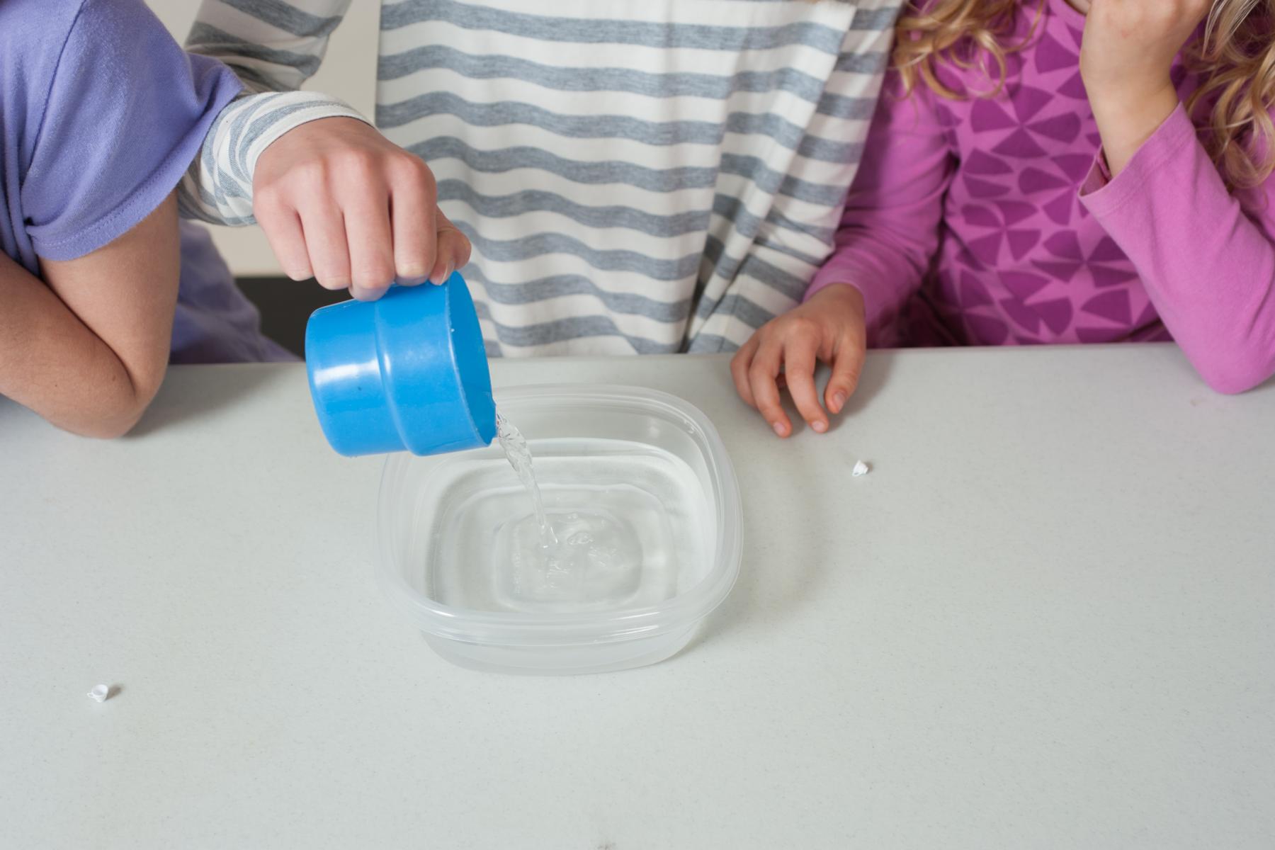 Photo of learners comparing what happens to water that is poured from a big cup vs from a tiny cup