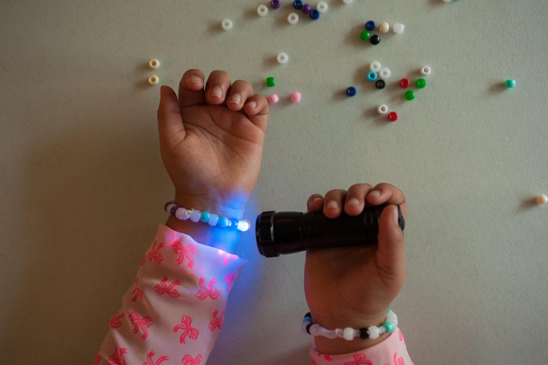 A black light shining on a UV color changing beaded bracelet