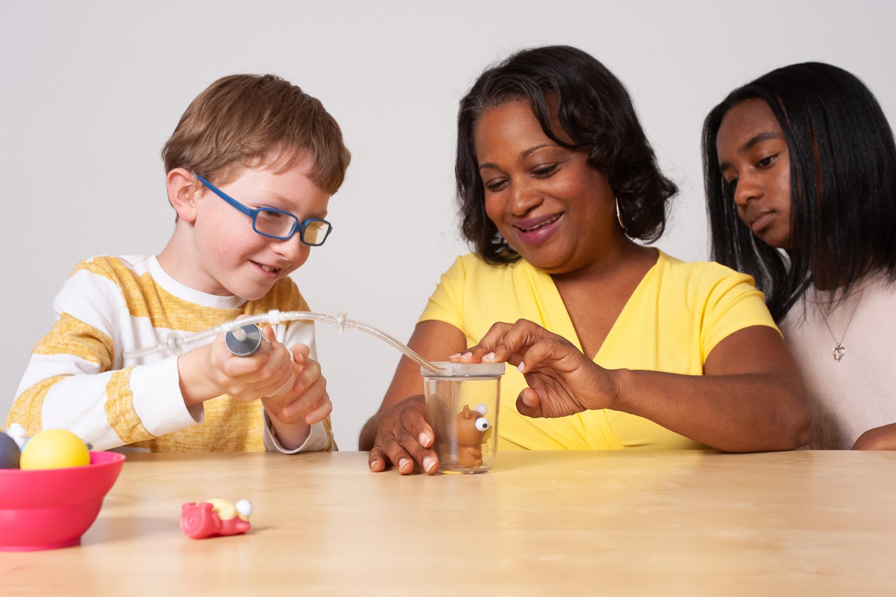 Family of three filling a small chamber with air with a small squish toy within