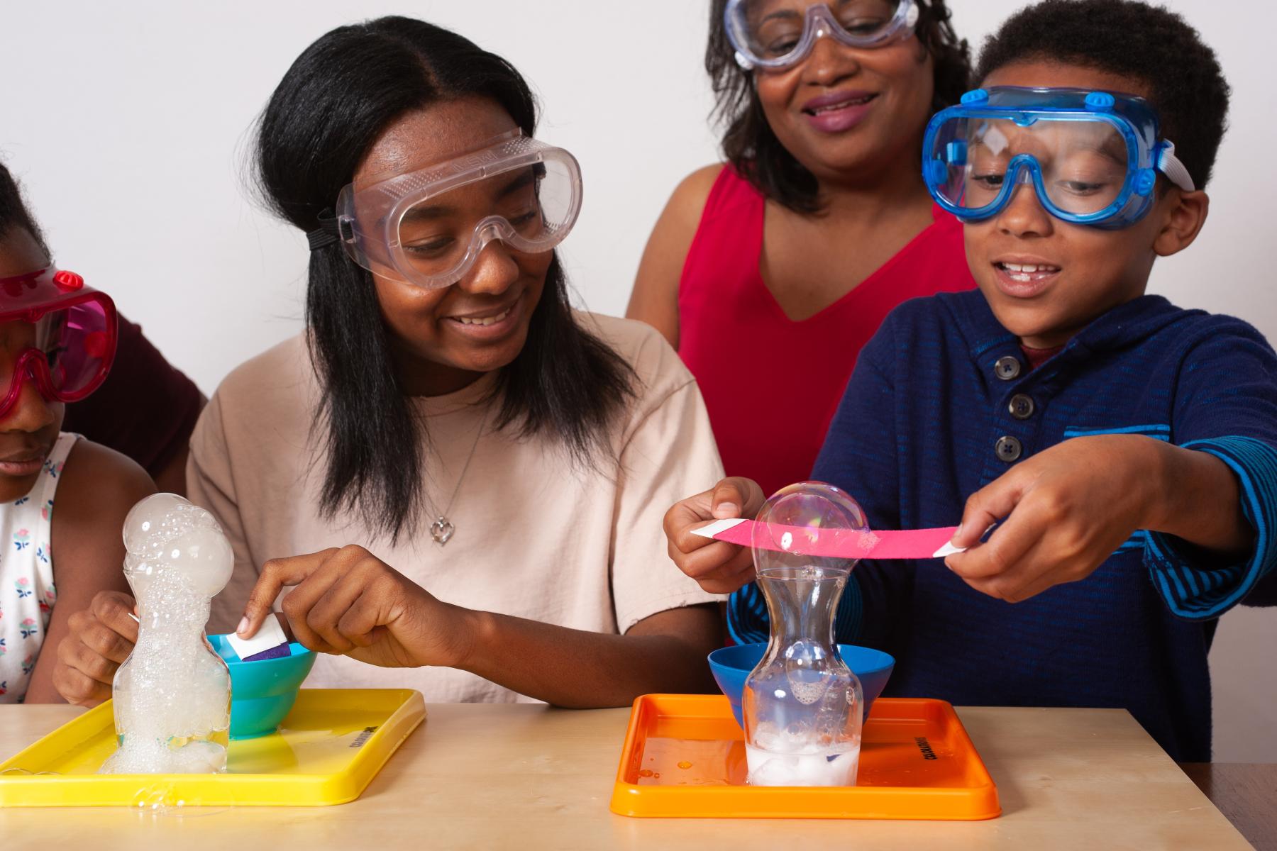 Two learners and a facilitator layer a bubble with a felt strip onto another bubble