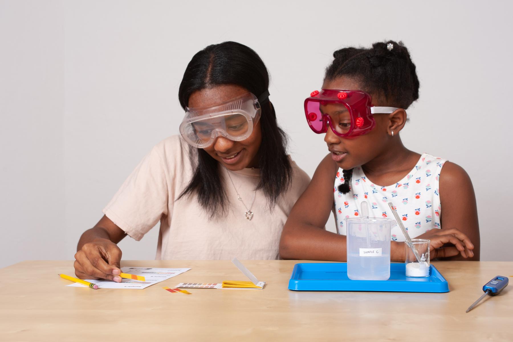 Two learners record the pH reading from a pH testing strip