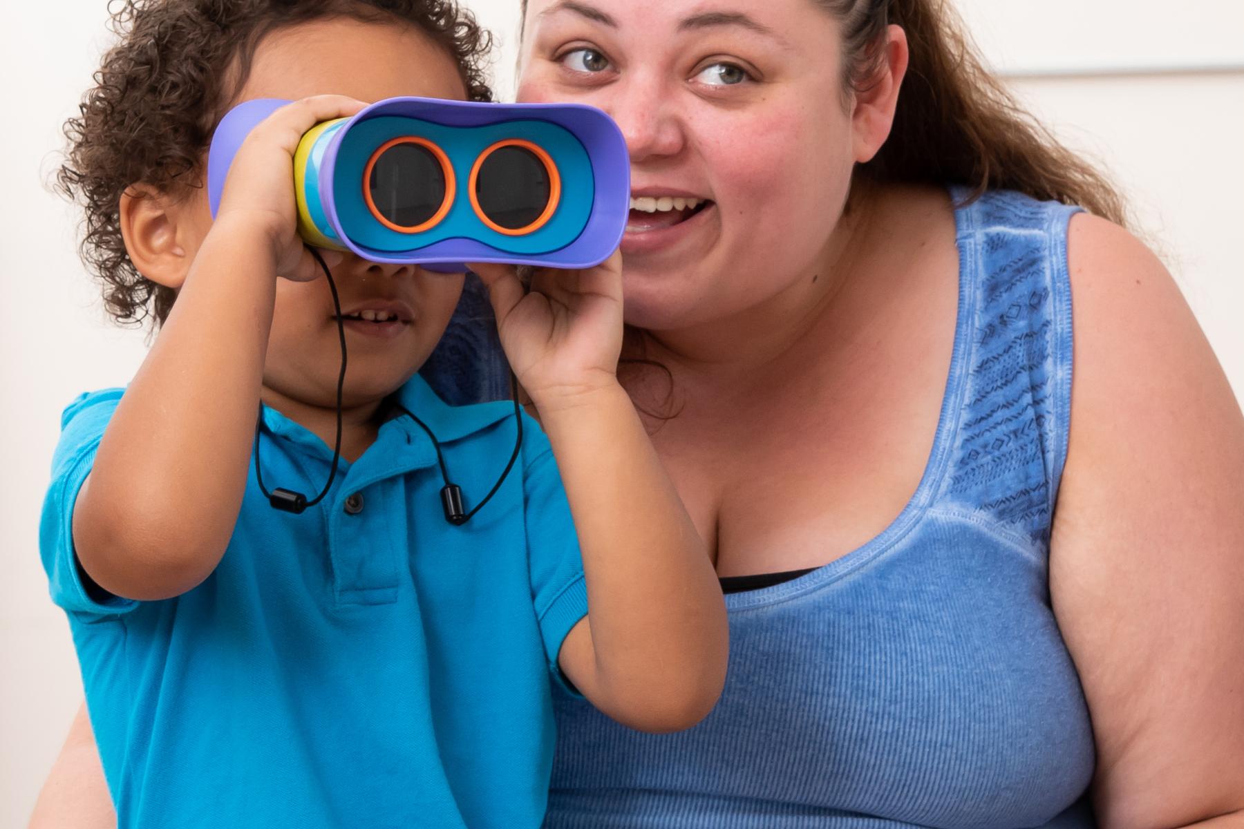facilitator and young learner use binoculars to look at a moon poster