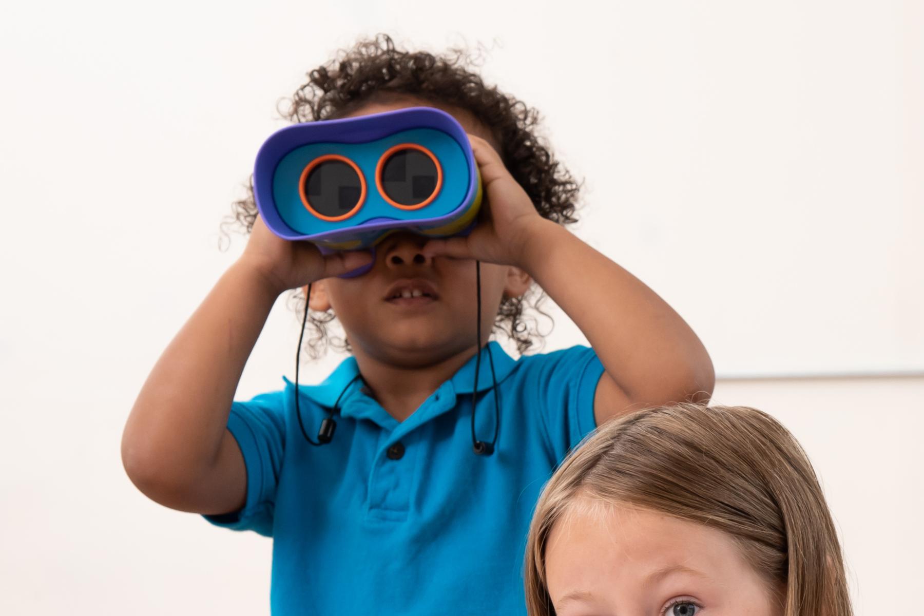 Two young learners using binoculars and drawing what they see