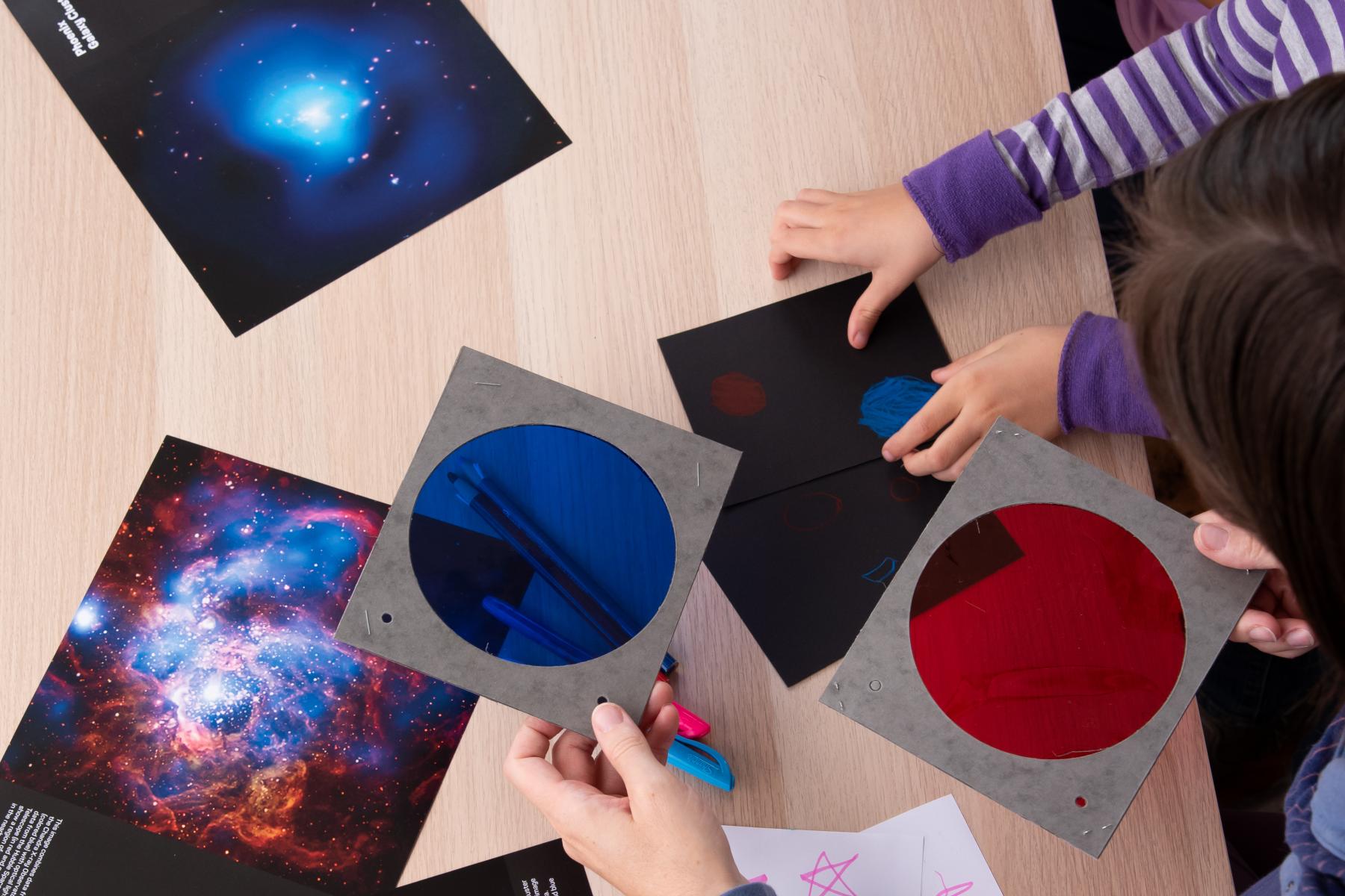 Group of learners use blue and red filters to examine photos of different nebula