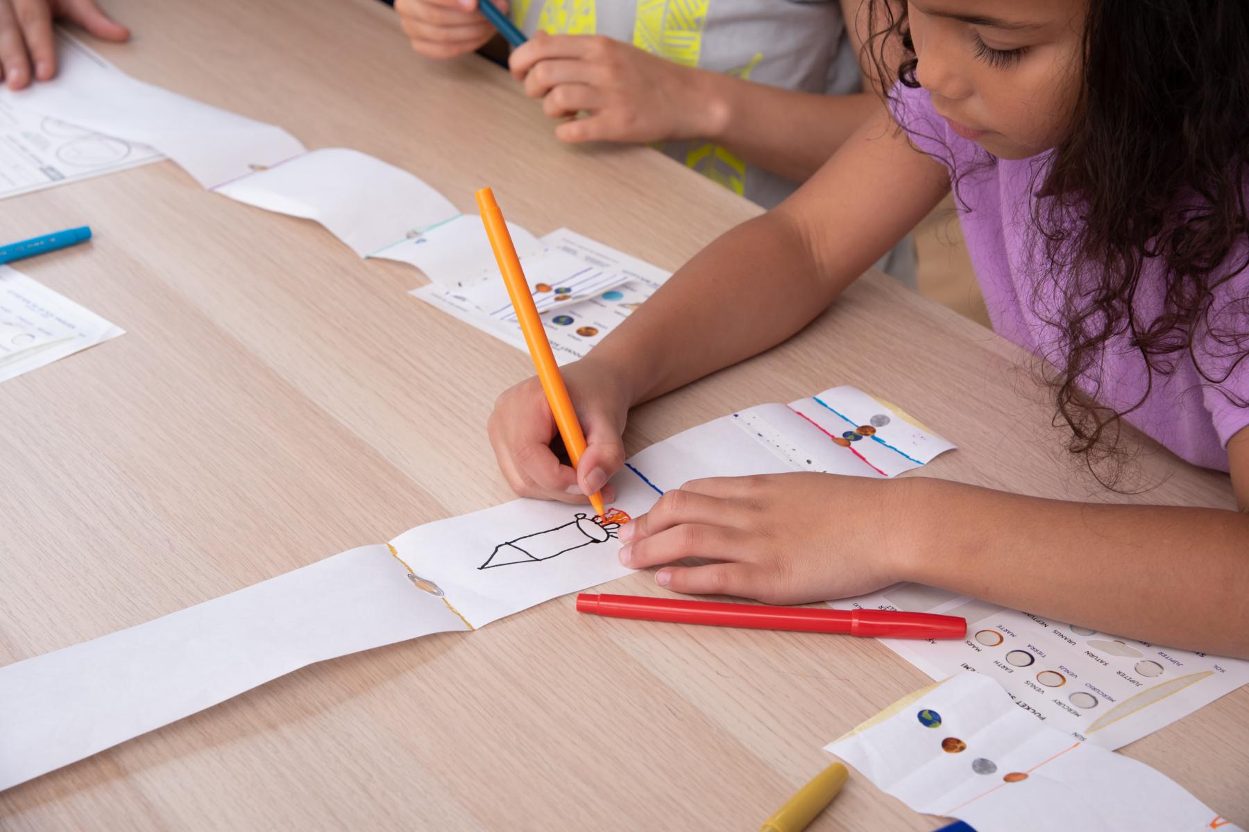 Image of a learner drawing a rocket on her pocket solar system 