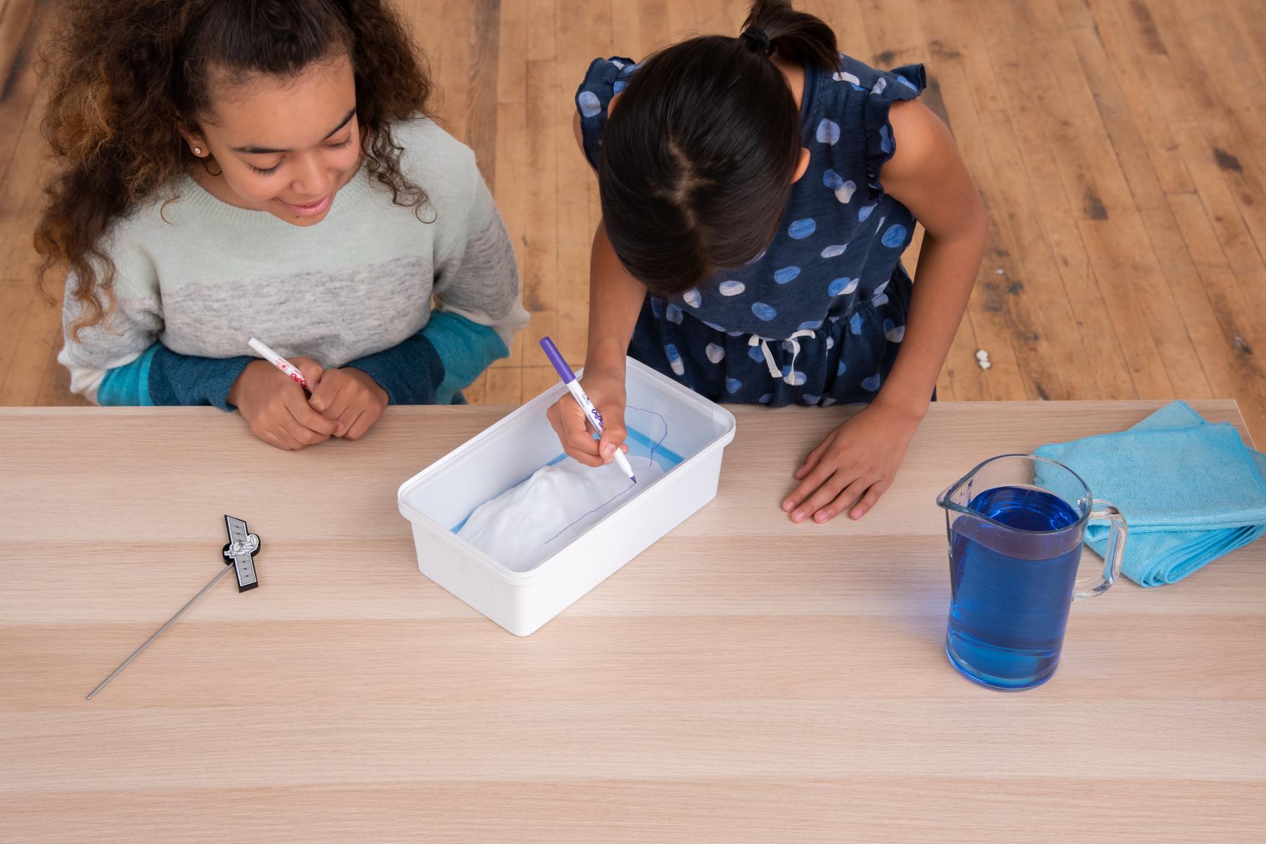 Two learners trace a low water line on clear piece of plastic