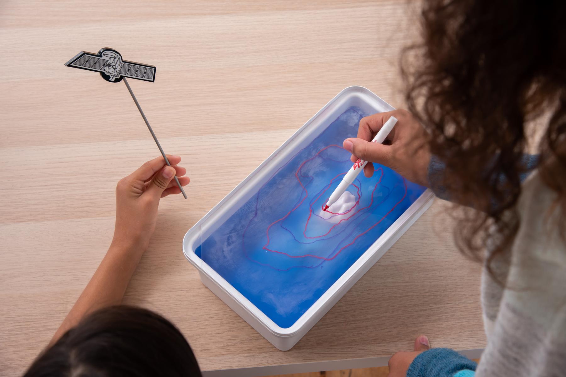 Two learners trace a high water on clear piece of plastic