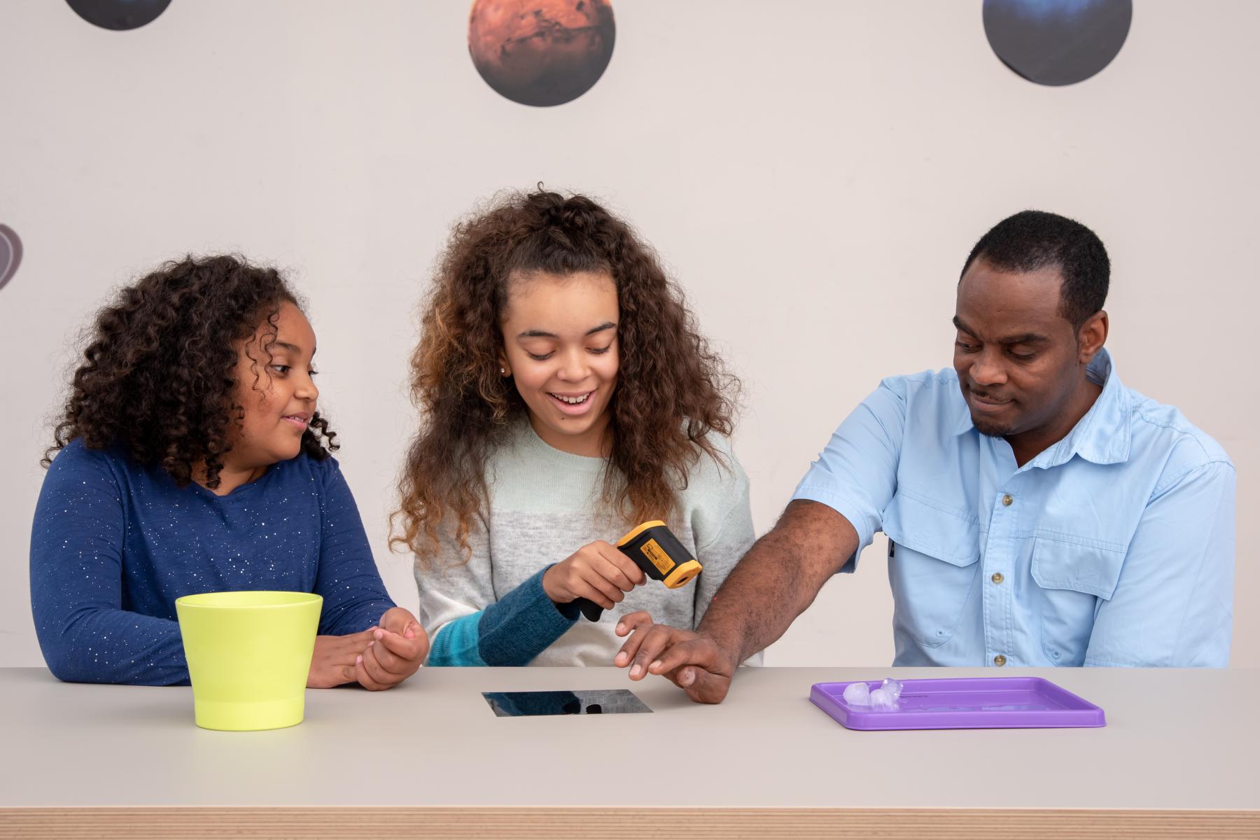 Family using thermometer to take temperature of their arm for the Heat Map activity