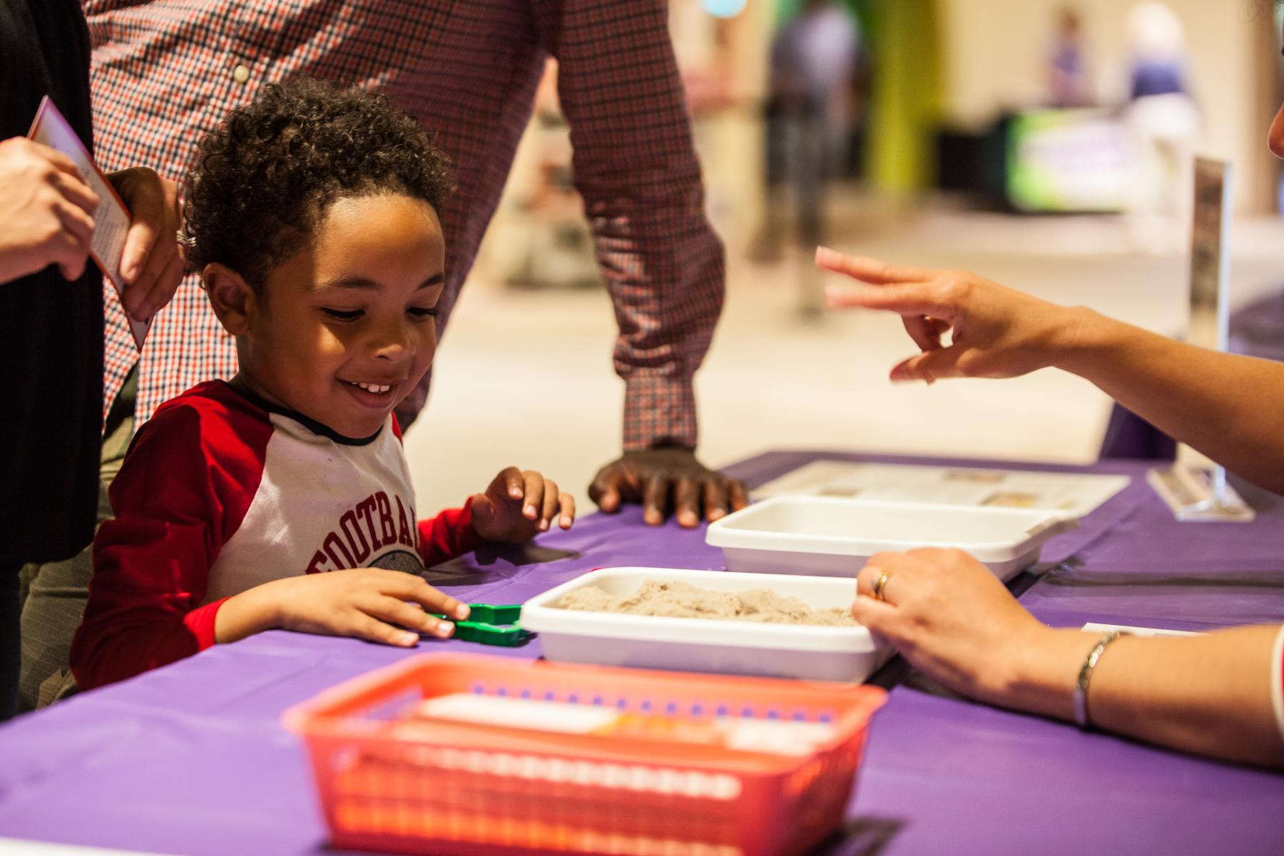 Young learner interacts with kinetic sand in a tray