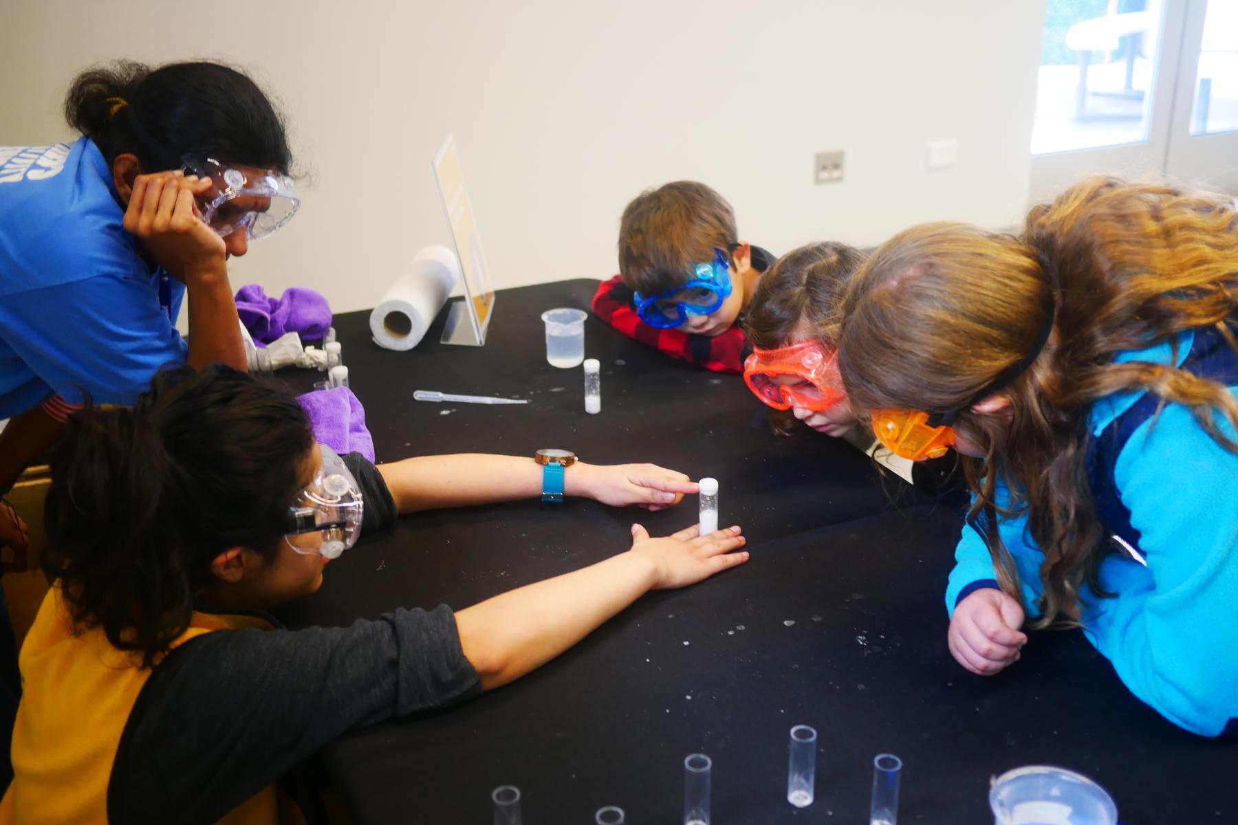 Two facilitators and a group of learners wait for their chemical reaction in a small tube to take place