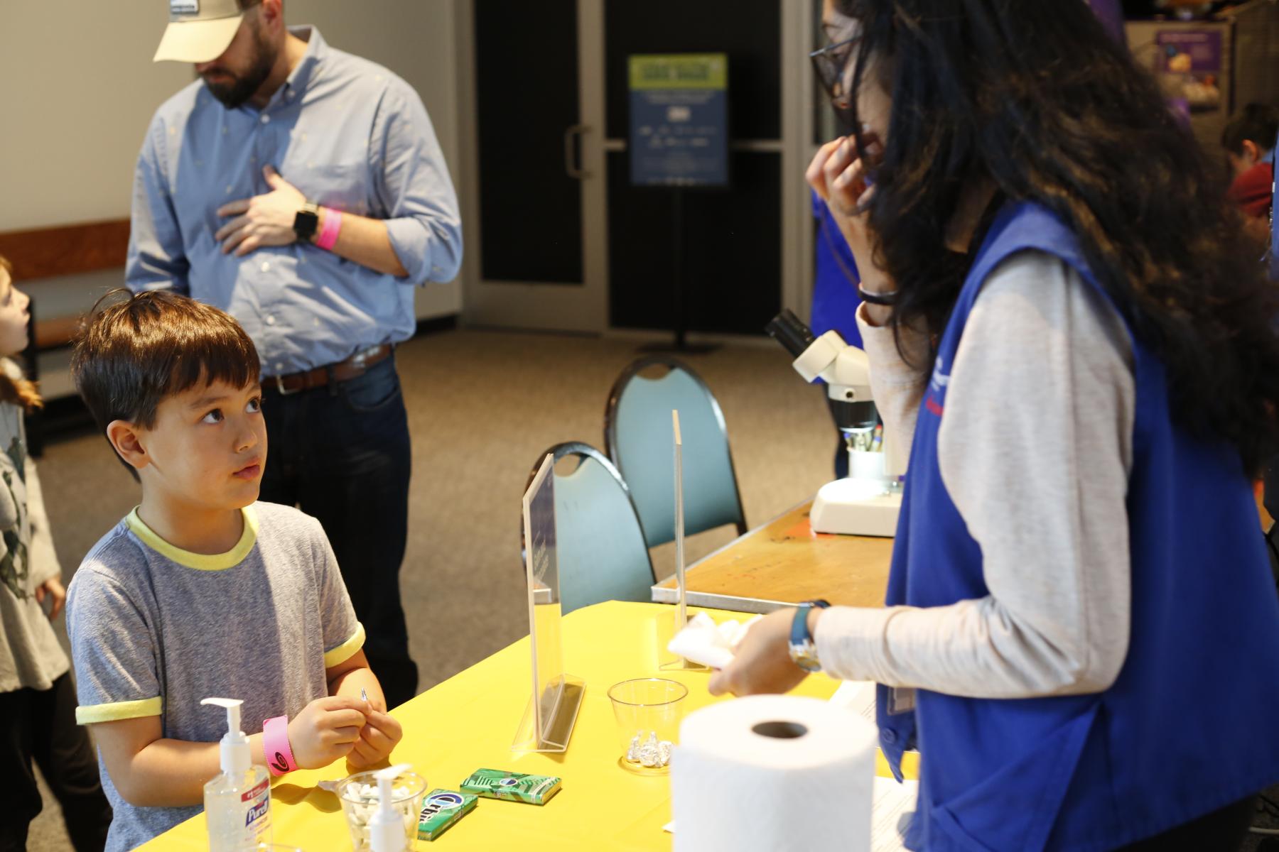 A facilitator demonstrates how to mix and chew gum with a piece of chocolate