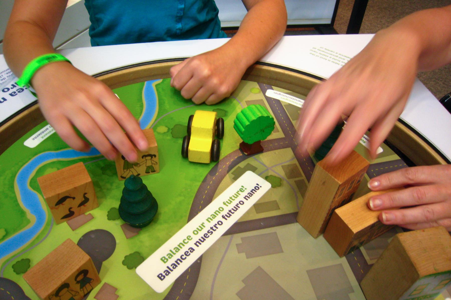 a close up of two sets of hands moving different wooden blocks on the balance table