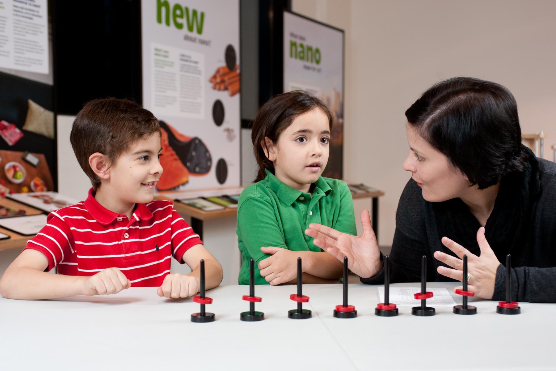 Facilitator discusses what Computer Hard Drives are with two young learners using small levitating magnets 