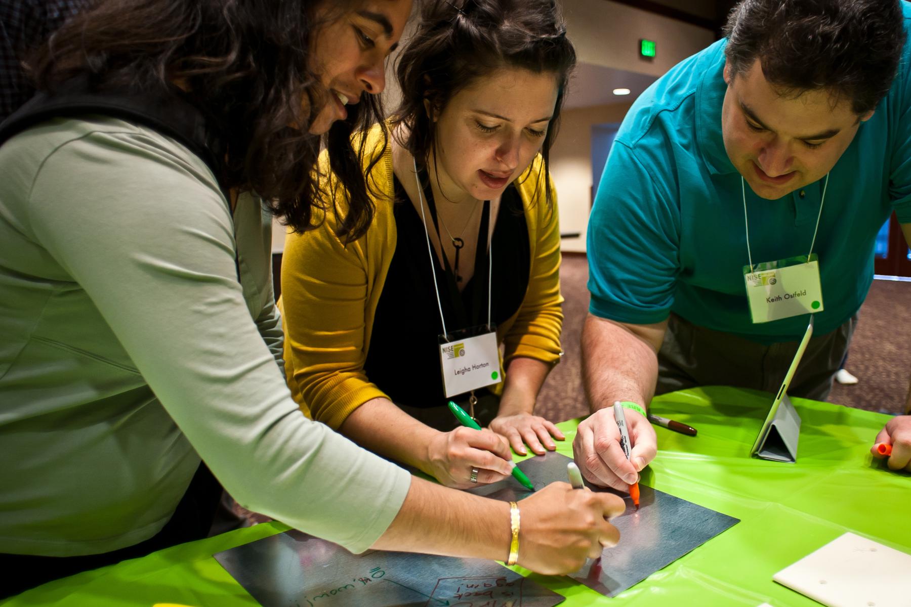 museum staff working together in professional development session with markers on graffiti activity on a nano coated surface on a metal plate