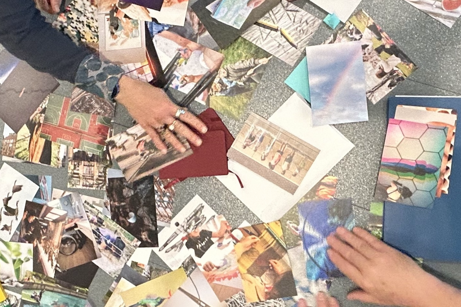 What is learning photo cards spread out on a table with people's hands sorting through them