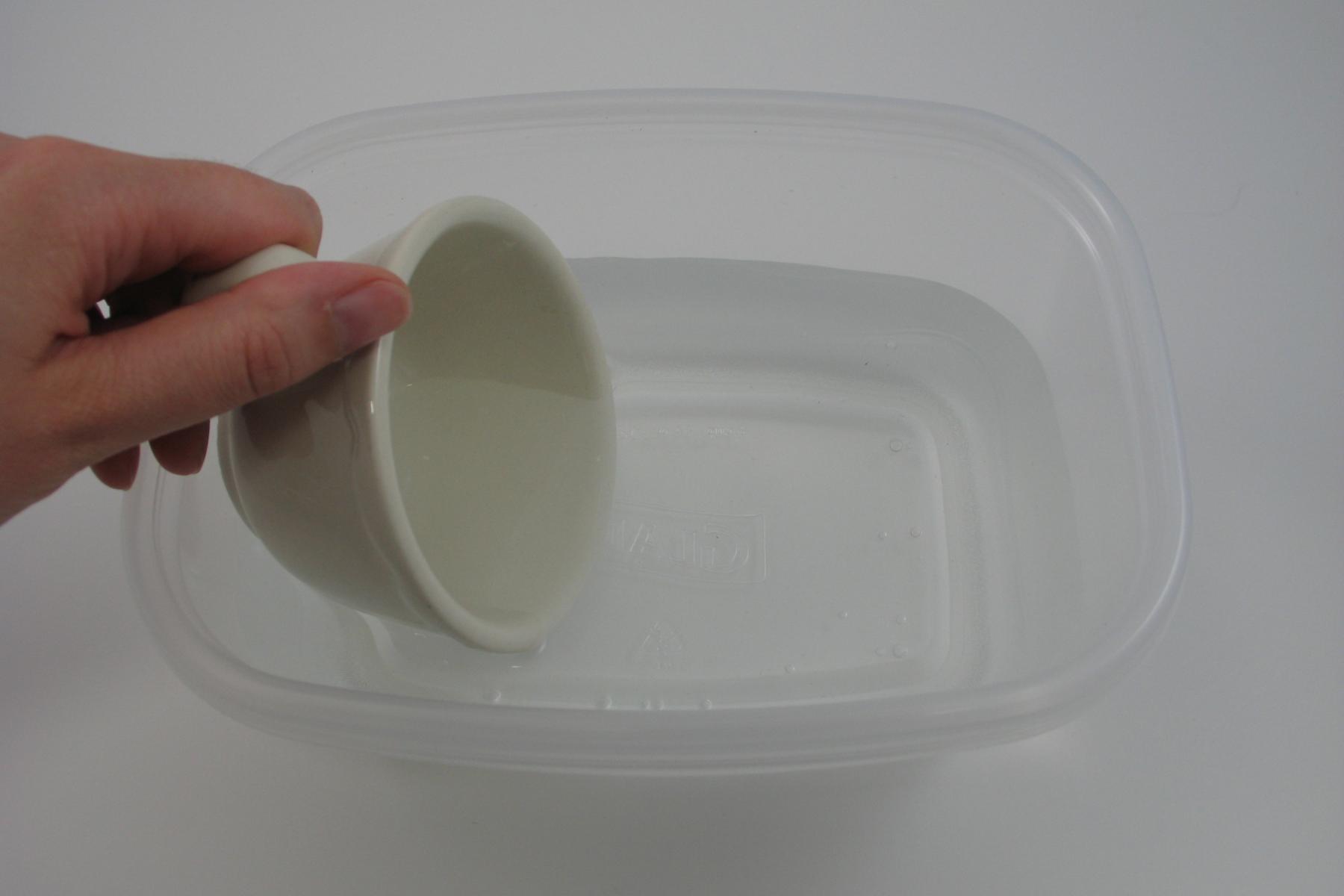 Hand filling life sized teacup with water in Zoom into Nano Exploring Forces - Gravity activity