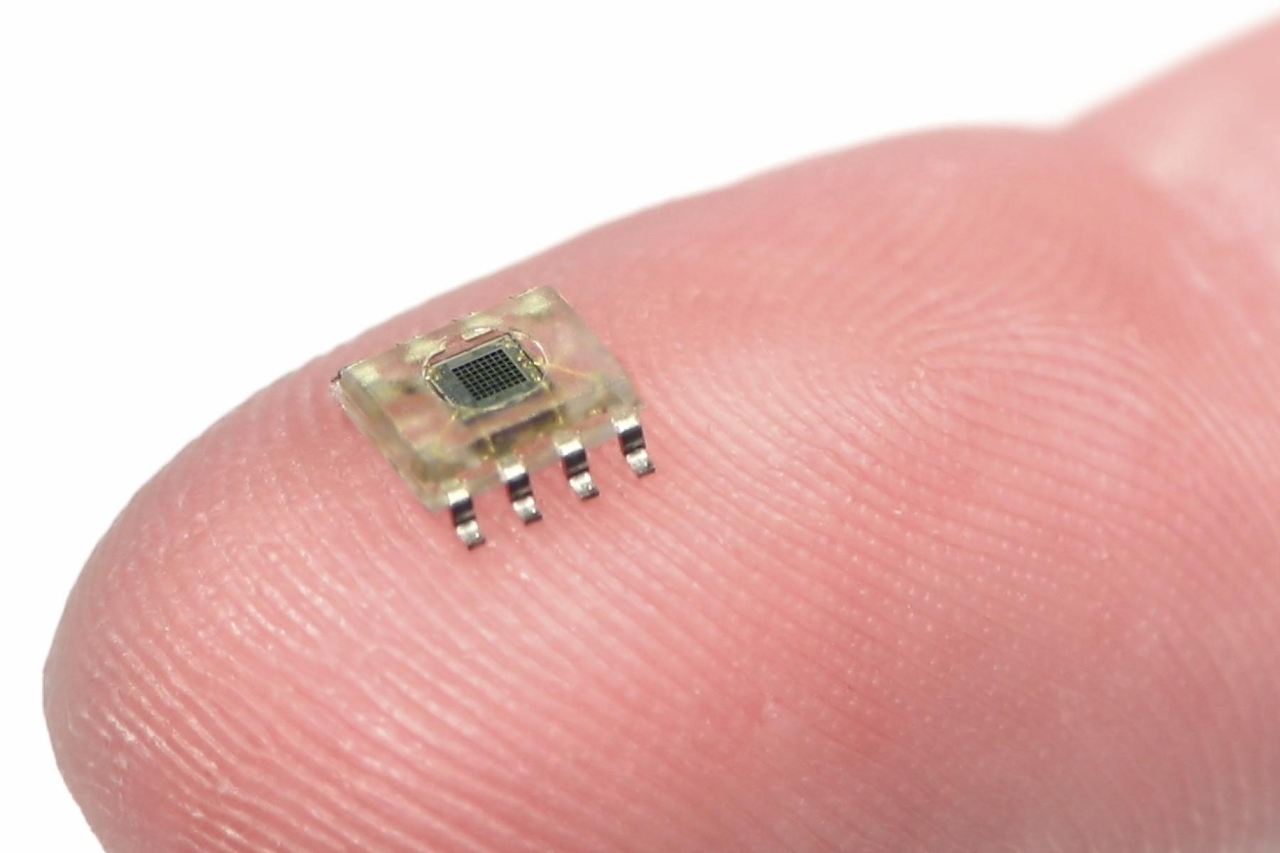 A small microchip lying on a person's fingertip.