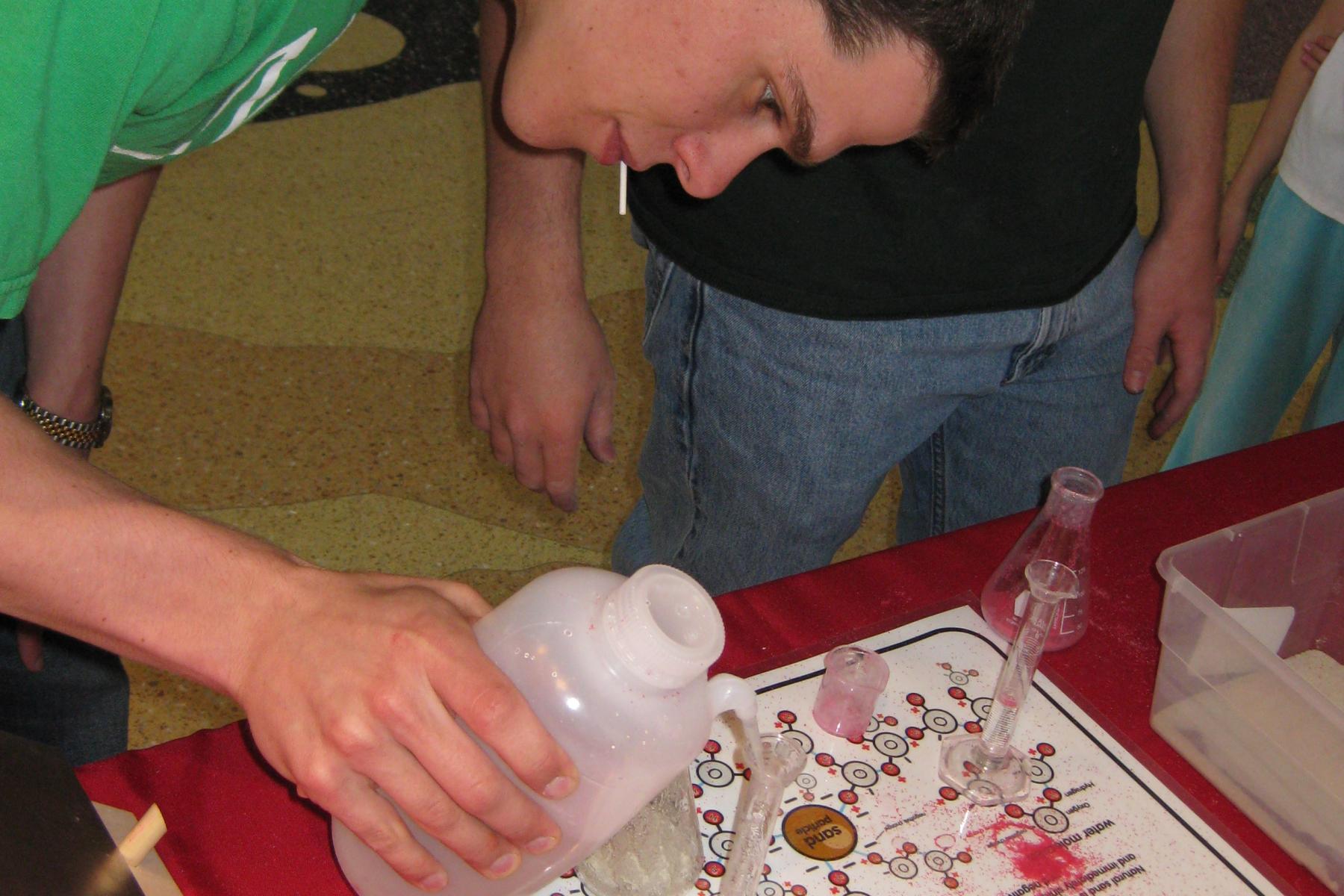 Learner pours water into a flask of magic sand