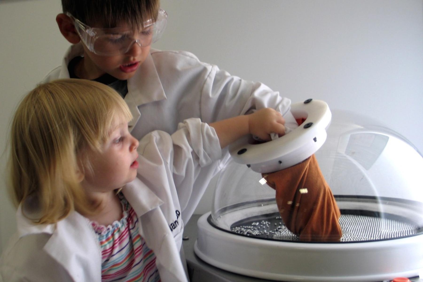 Little boy and girl looking using glove in an alcove in the NanoLab exhibit