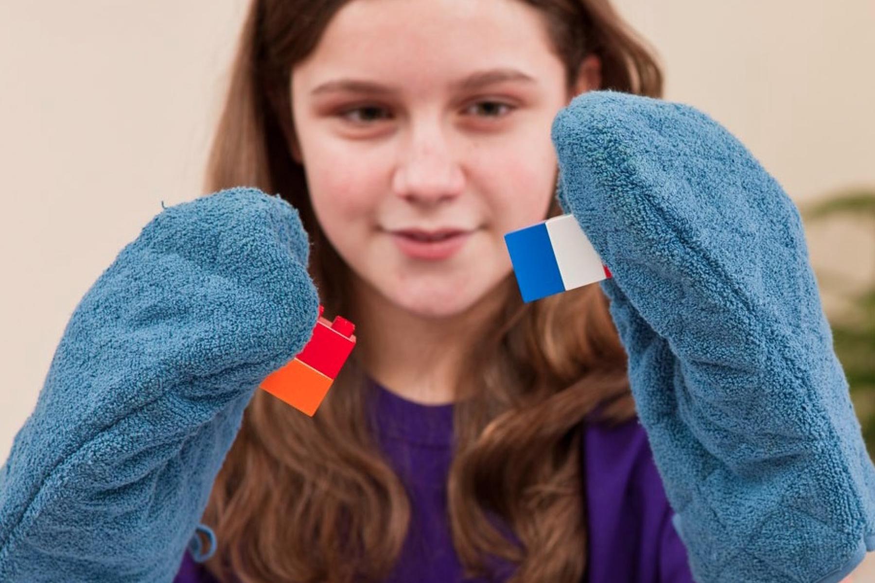 Girl holding building blogs while wearing oven mittens