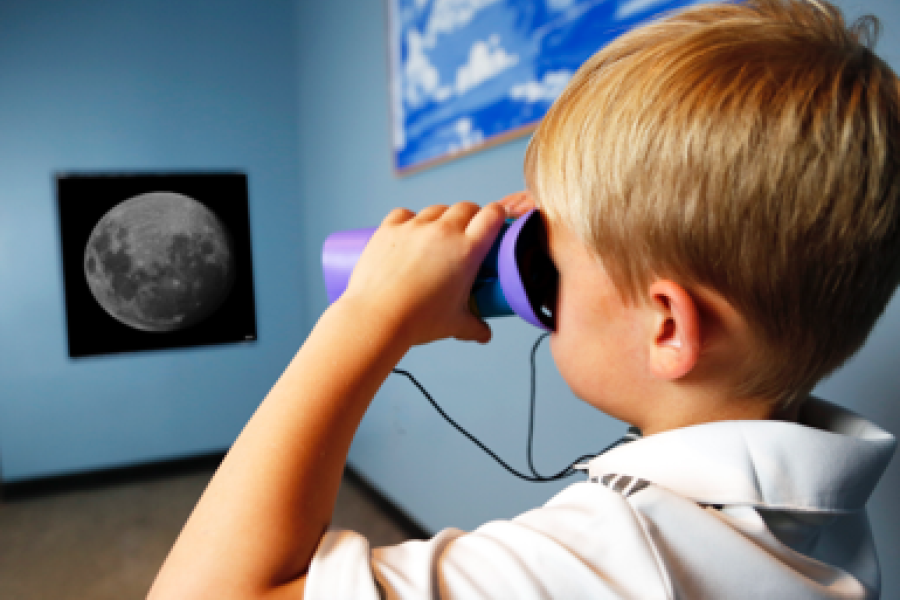 Child using binoculars to look at an enlarged photo of the Moon in Hide and Seek Moon activity 