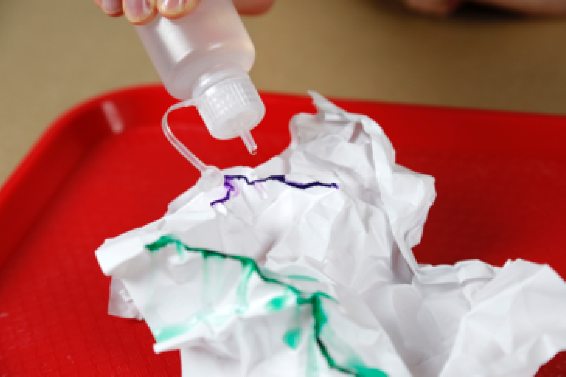 Person dripping water on crinkled paper to demonstrate water flow