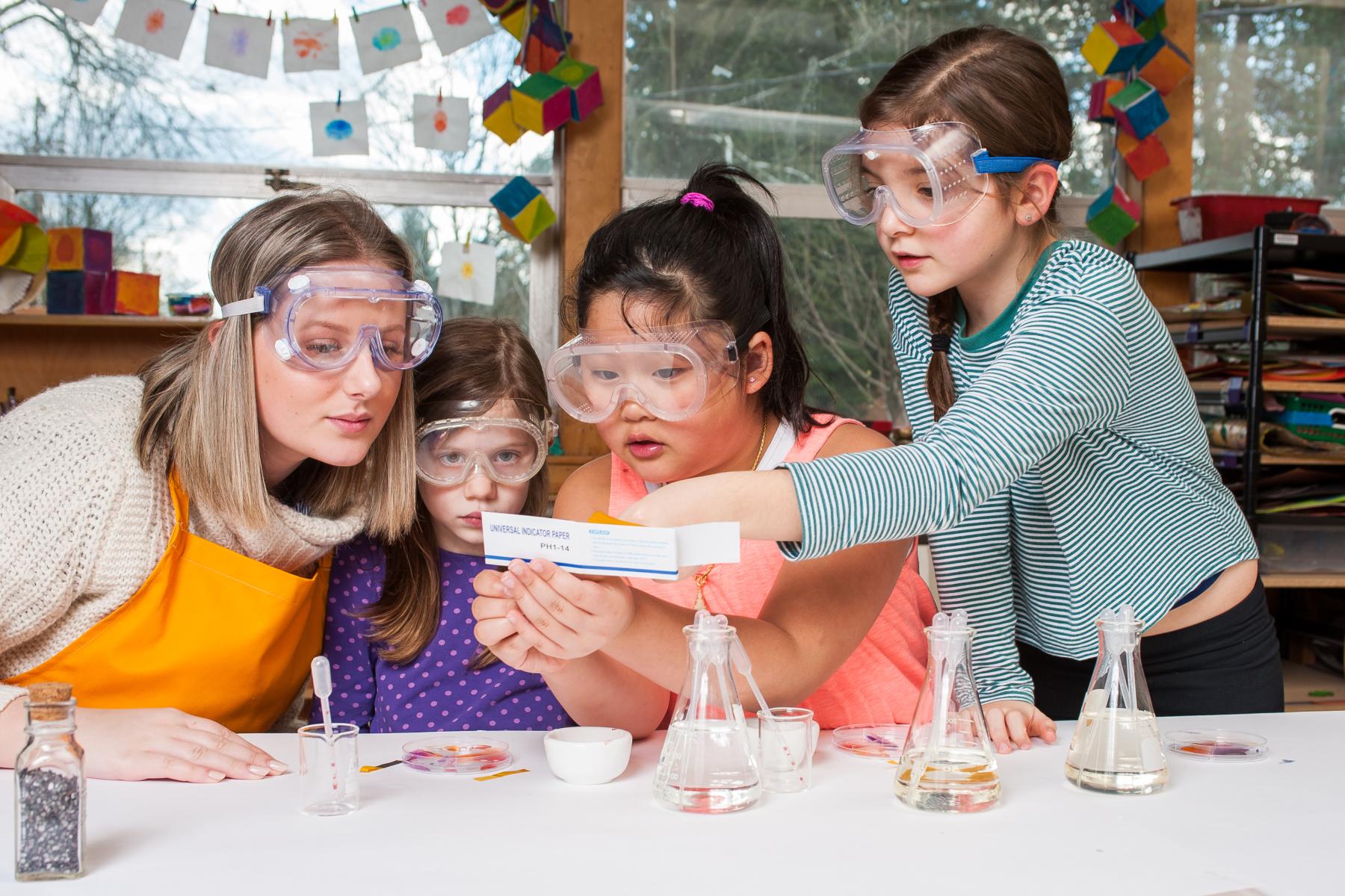 Three learners and a facilitator compare their dye colors to a PH scale