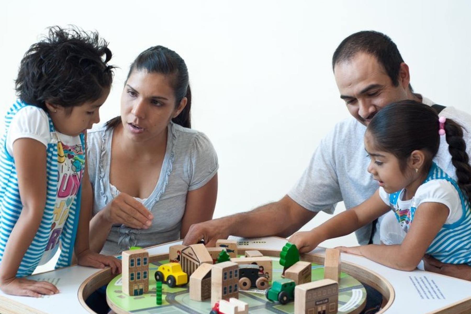 family using a balancing table with wooden blocks to talk about Nano in society 