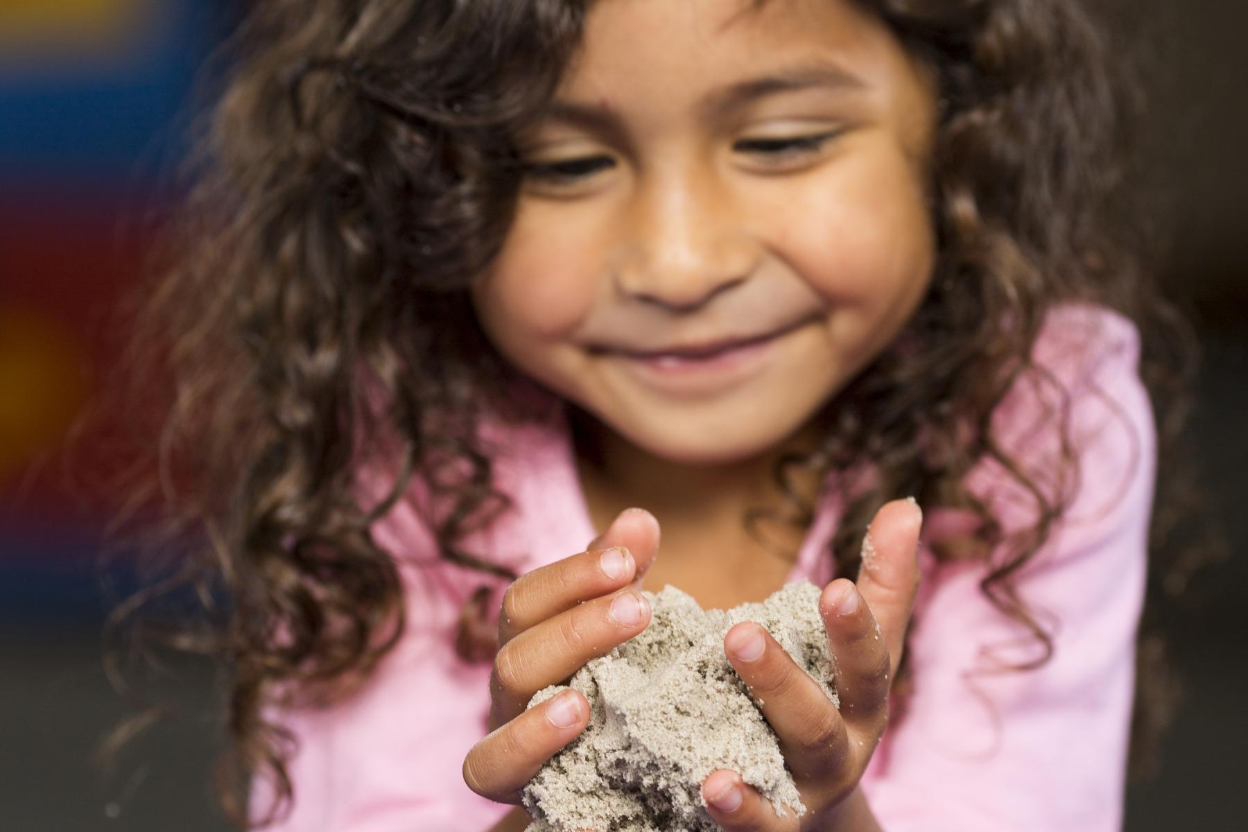 Girl holding sand in hands