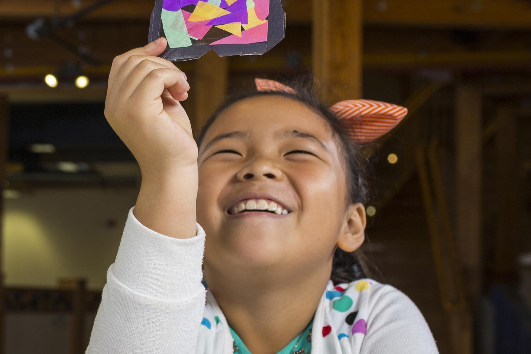 Girl looking at stained glass craft using NanoDays Exploring Materials - Stained-Glass Windows