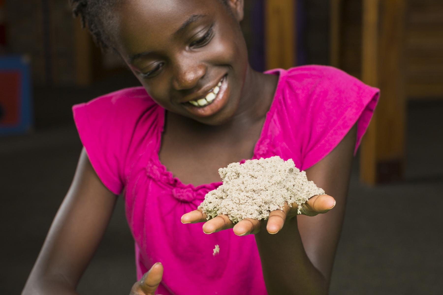 girl in pink shirt holds kinetic sand