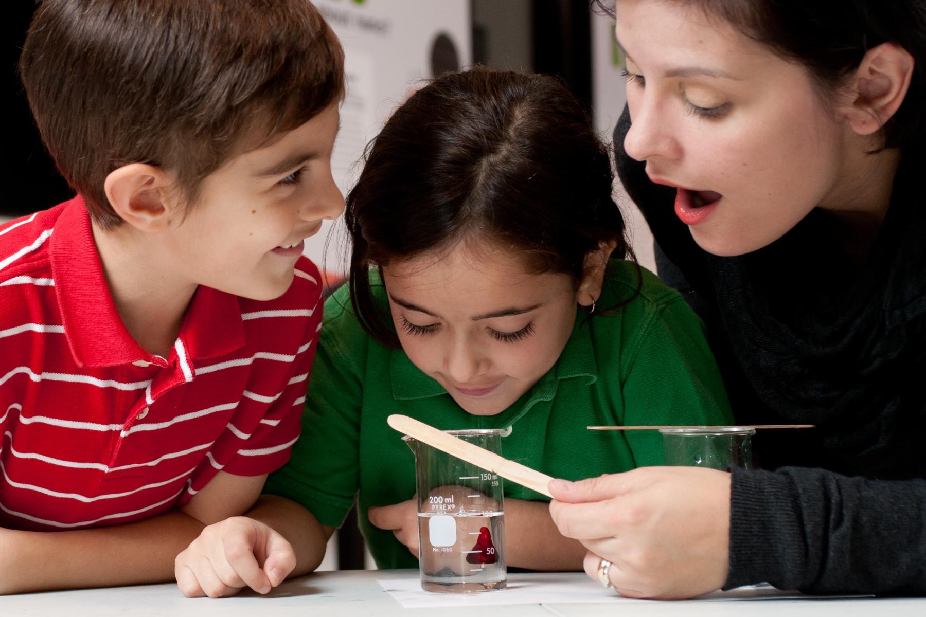 A family is looking at how light makes something in a beaker seem as if it's disappearing.