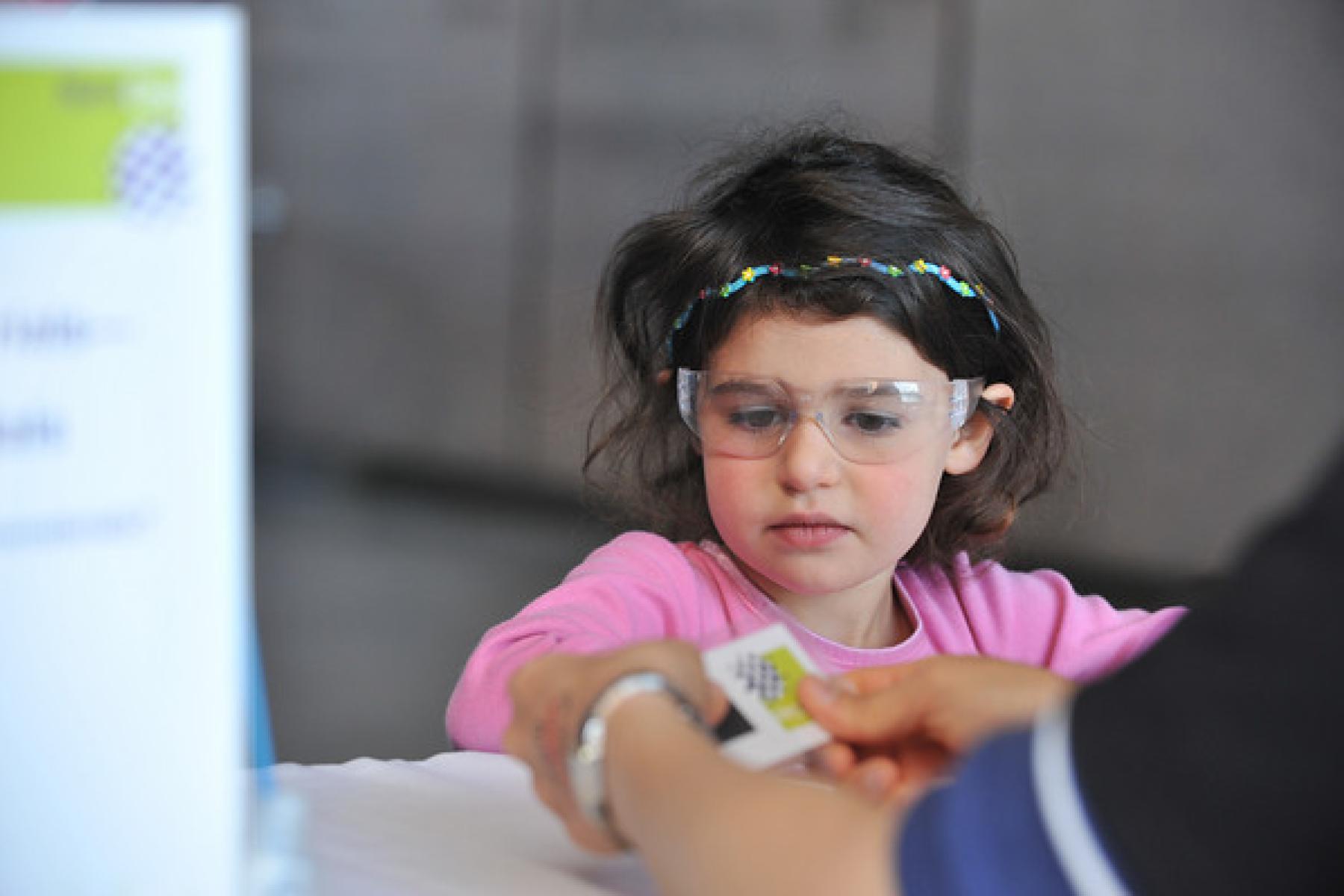 A girl in glasses getting a nano logo tattoo.