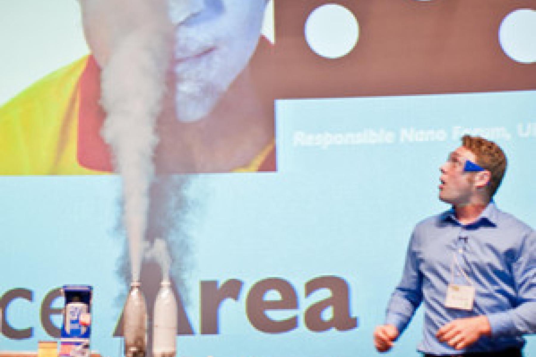 Educator on stage with aerosols coming out of bottle