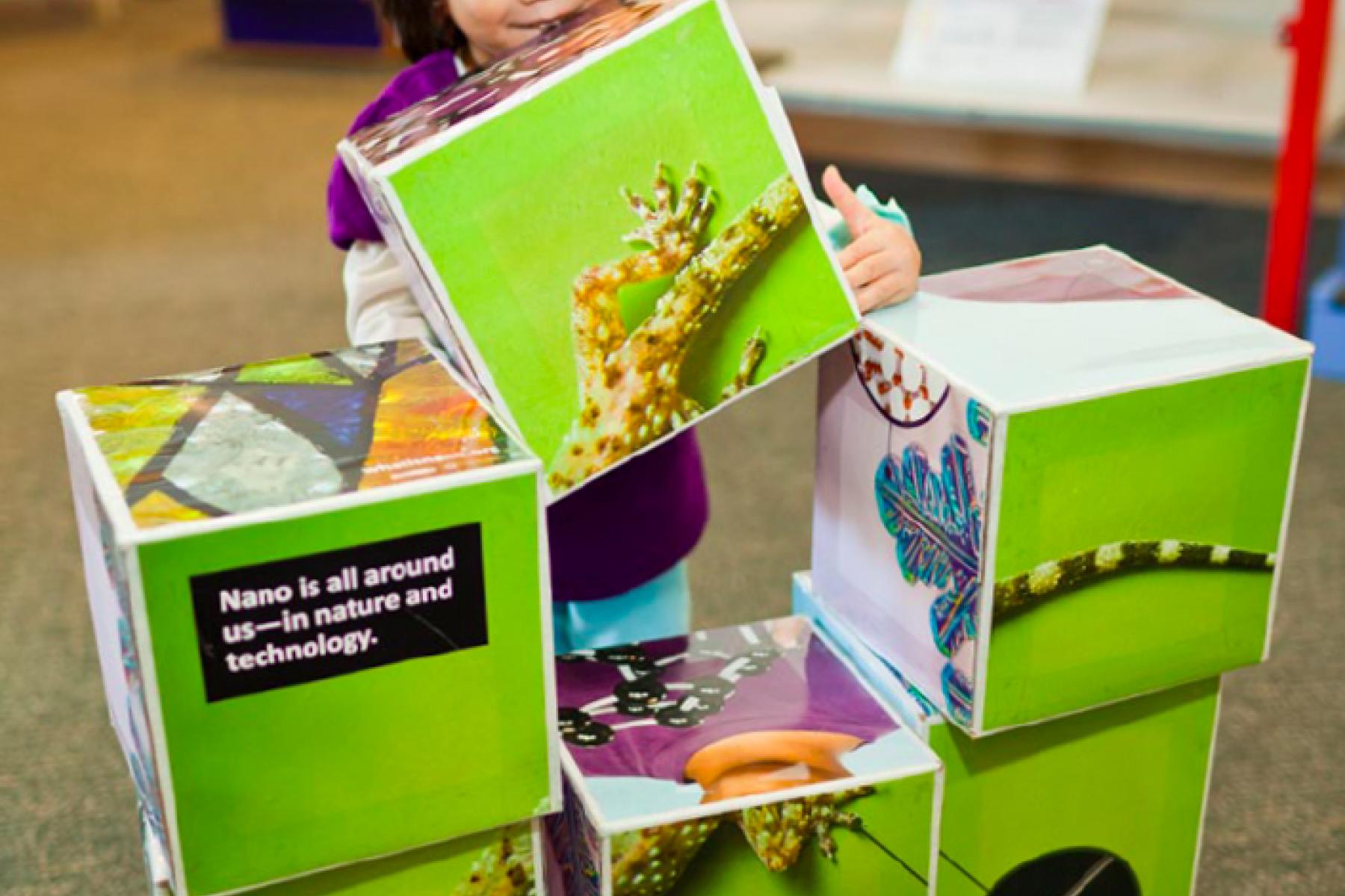 Young girl stacks large blocks with images on them