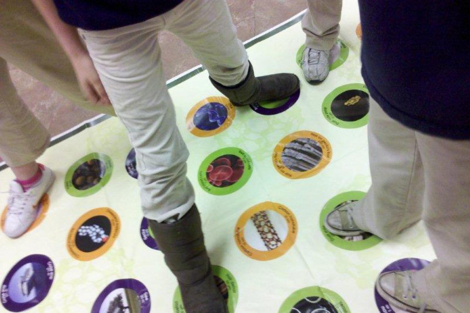 People playing Stretch-ability, a hand and foot game, on a mat.