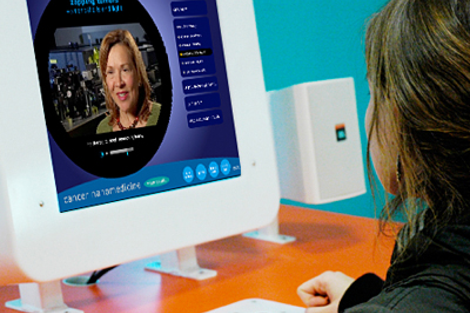 a young learner uses the Nanomedicine Exhibit, where a video plays on a computer monitor