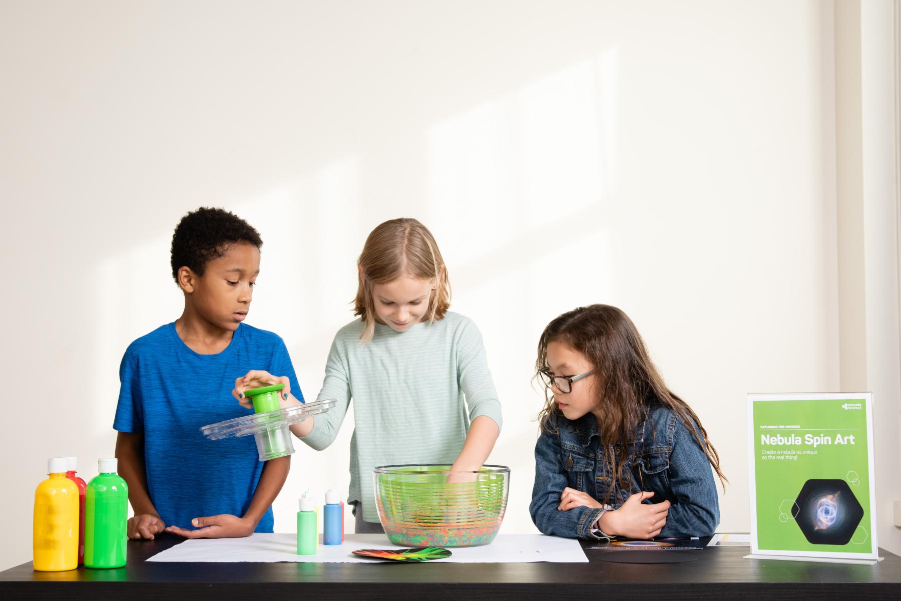 Three learners look at paint "nebula" in spinner