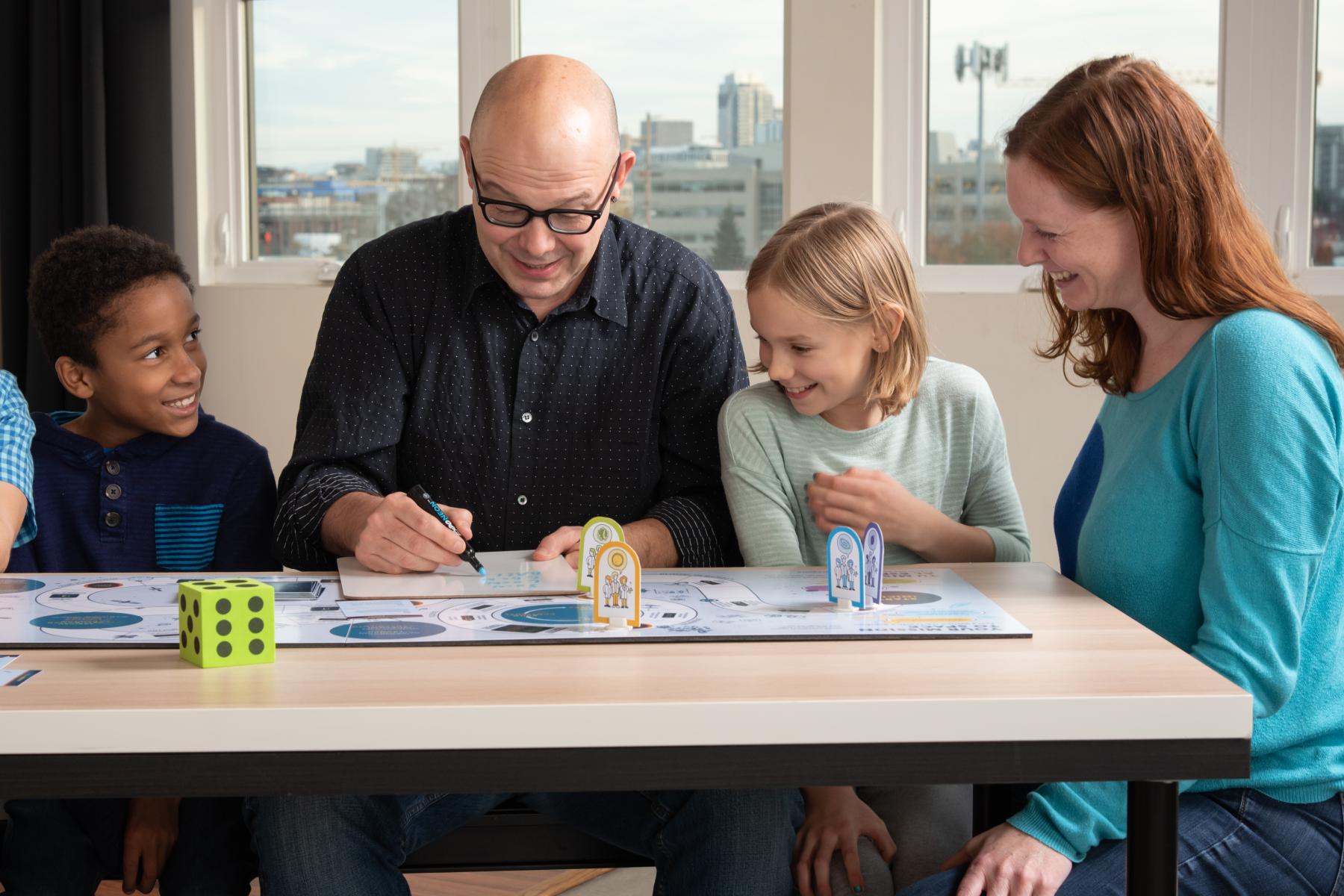 A family of four draws a challenge image on a whiteboard 