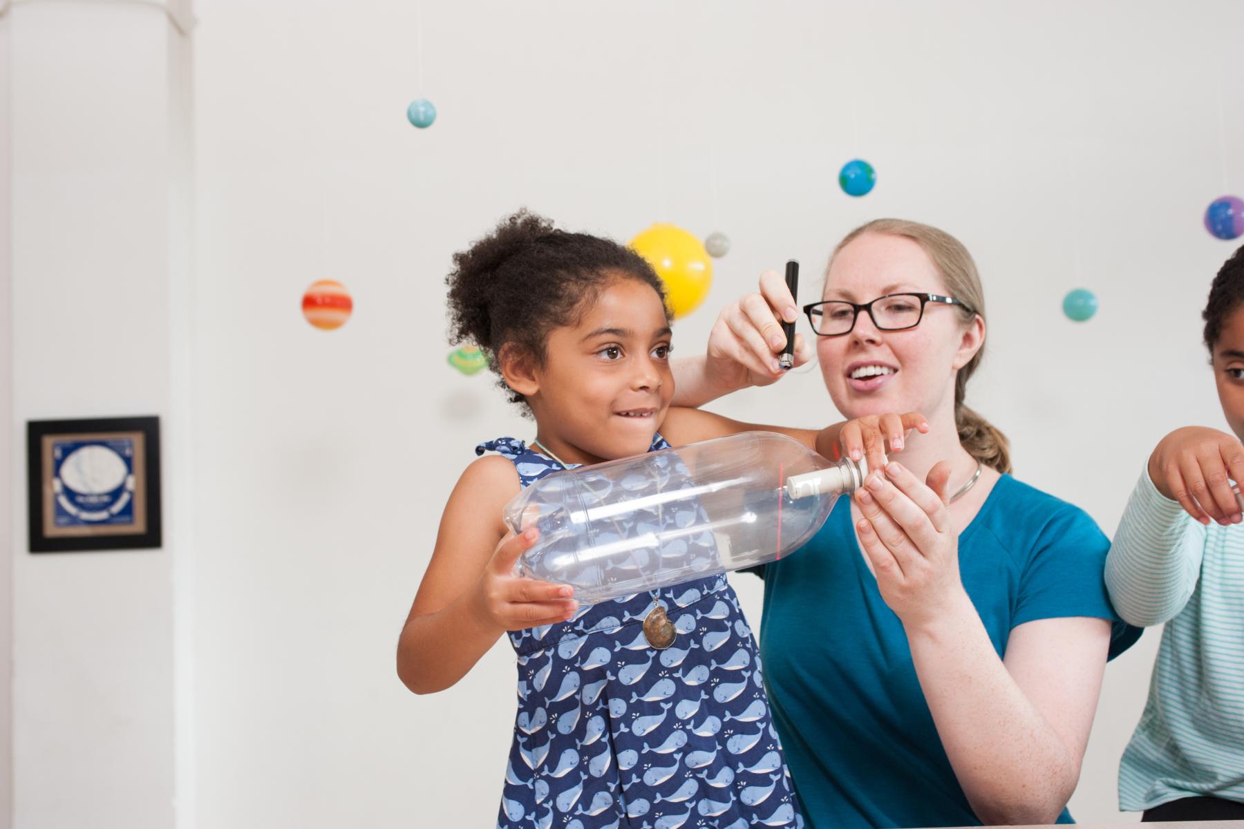 A learner and facilitator use a laser to observe a cloud made in a bottle 