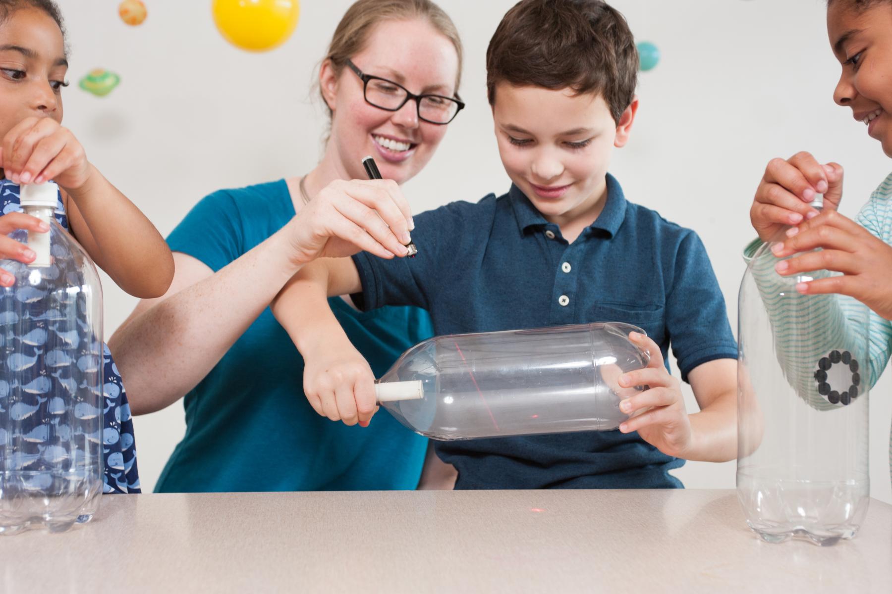 Three learners watch a cloud form in a bottle