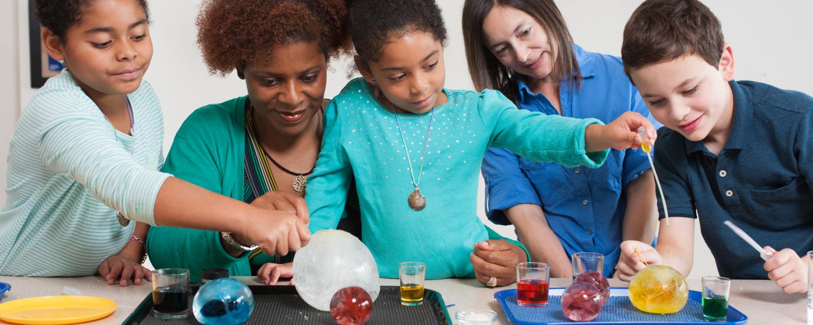 Children and adult investigating globes of ice in  Icy Orbs activity