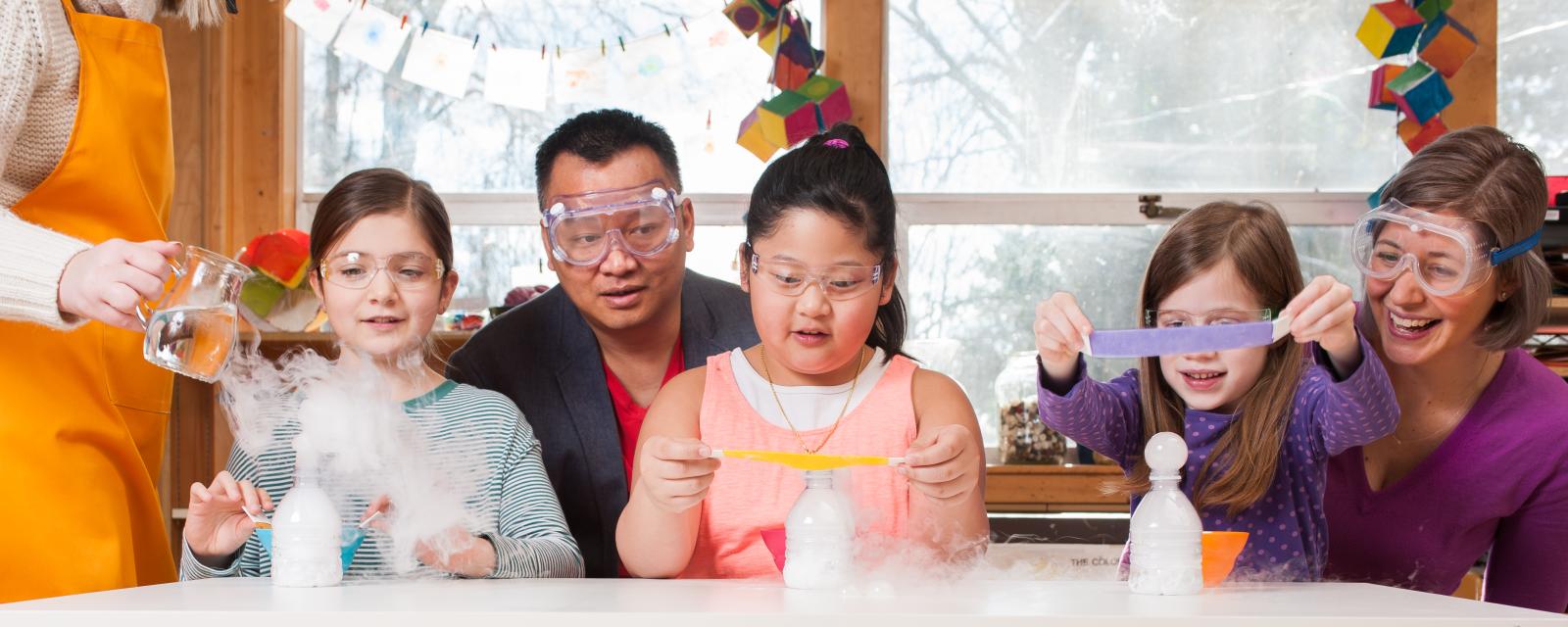 Group of children and adults using dry ice to make bubbles in Explore Science Let's Do Chemistry Sublimation Bubbles activity