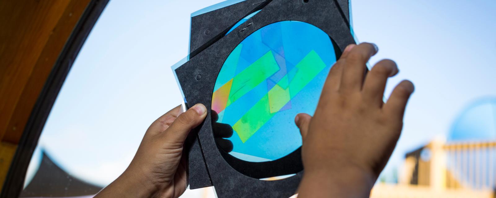 Polarized Light activity with hands holding paper and polarizing tape materials up to the window