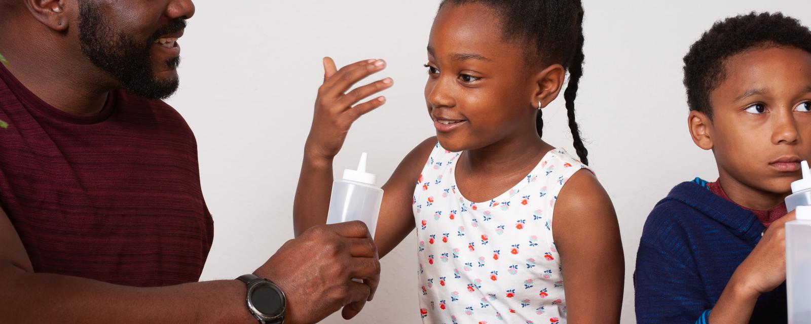 A facilitator holds a bottle while a learner wafts a scent to her nose