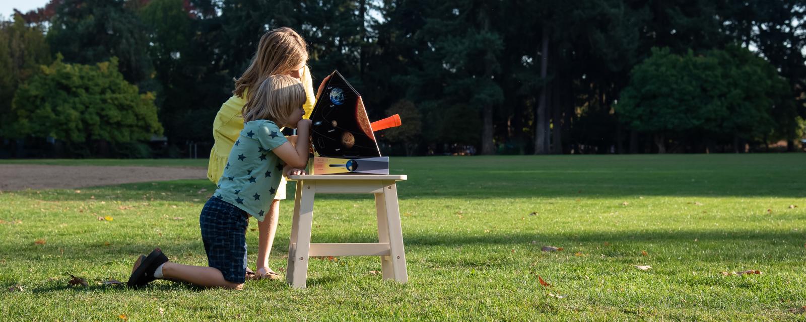 Two learners observe the Sun with a solarscope in a grassy field