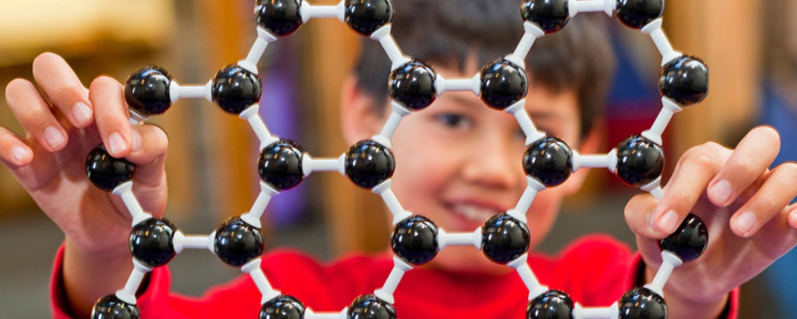 Learner holds up an atomic structure model of graphene
